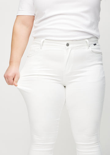Skinnyjeans för kvinnor i vit, färgen Marguerites. En plus size-modell drar i jeanstyget vid låret för att visa stretchen.