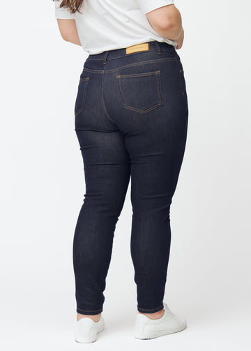 Djup mörkblå denim jeans för kvinnor i färgen Midnights sedd bakifrån på plus-size-modell.