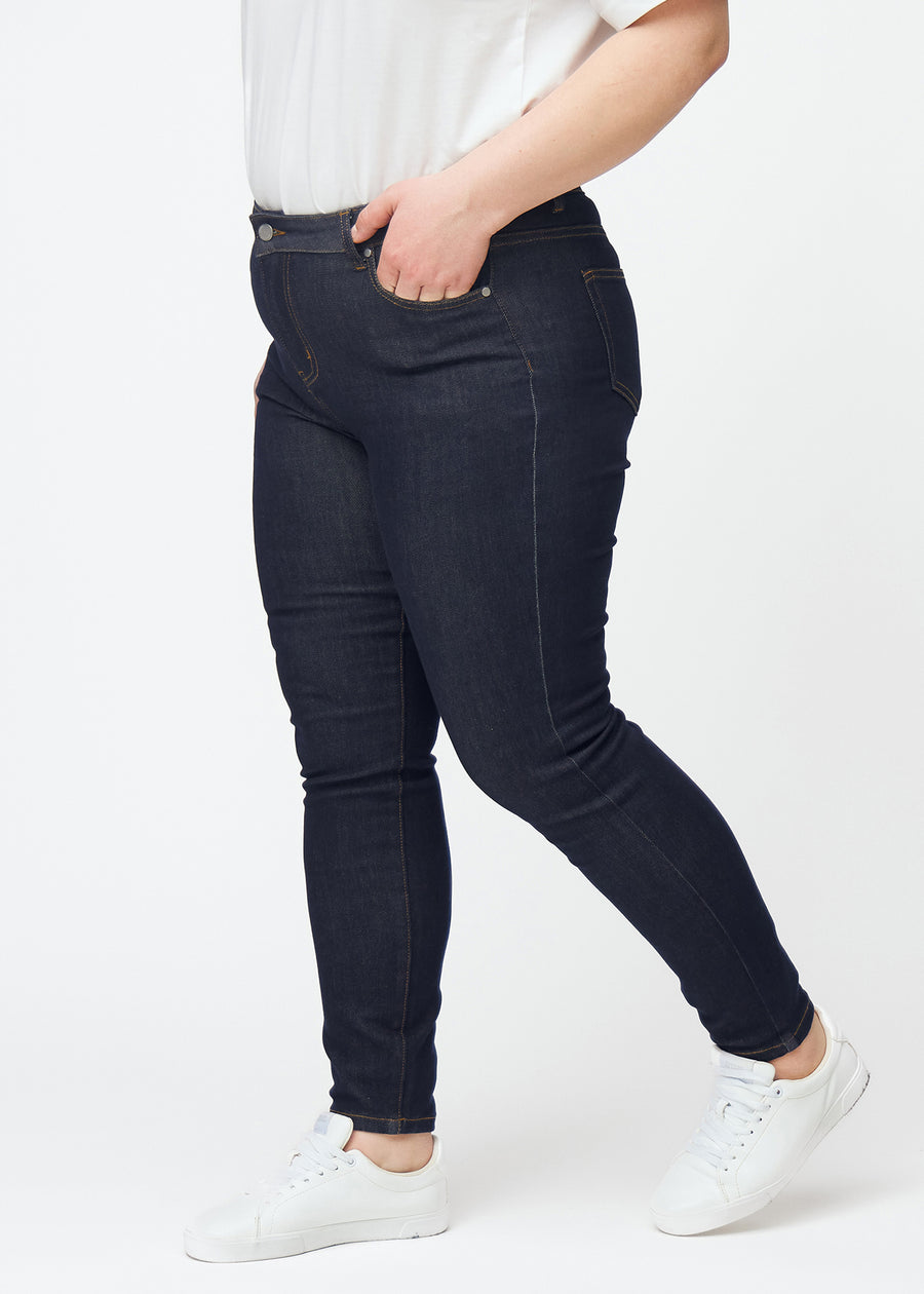 Djup mörkblå denim jeans för kvinnor i färgen Midnights med skinny passform sedd från sidan på plus-size-modell.