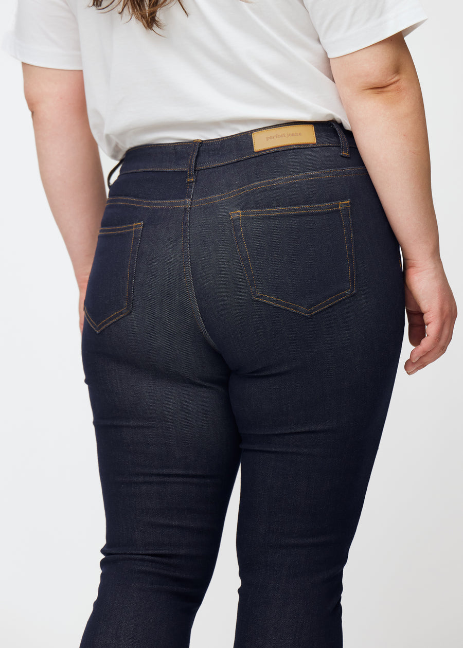 Djup mörkblå denim jeans för kvinnor i färgen Midnights sedd bakifrån i närbild på plus-size-modell.