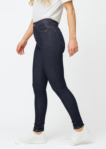 Djup mörkblå denim jeans för kvinnor i färgen Midnights med skinny passform sedd från sidan på modell.