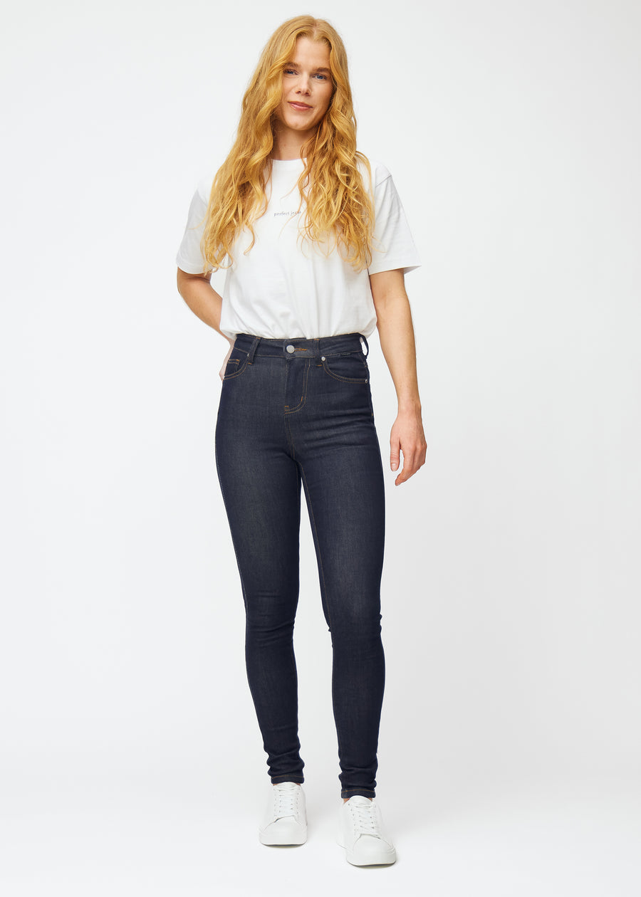 Helbild av modell i djup mörkblå denim jeans för kvinnor i färgen Midnights med skinny passform.