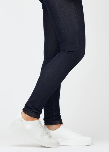 Djup mörkblå denim jeans för kvinnor i färgen Midnights med skinny passform sedd i närbild vid anklarna för att visa den tätsittande avslutningen.