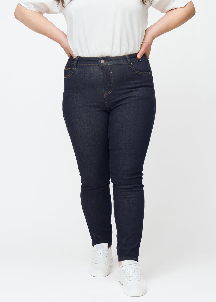 Djup mörkblå denim jeans för kvinnor i färgen Midnights med skinny passform sedd framifrån på plus-size-modell.