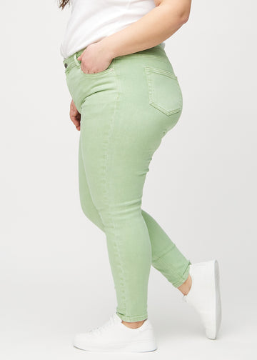 Ljusgröna skinny jeans sedda från sidan på en plus-size-modell.