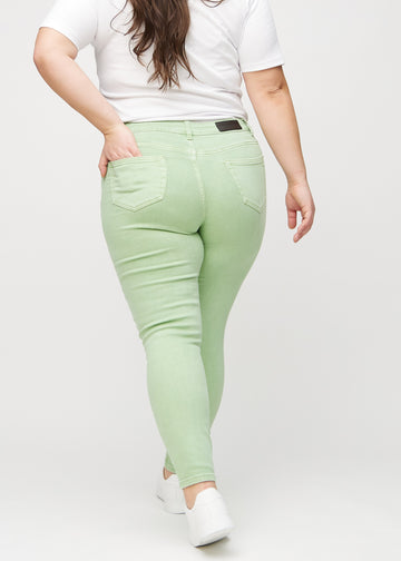 Ljusgröna skinny jeans sedda bakifrån på en plus-size-modell, så att man kan se hela produkten.