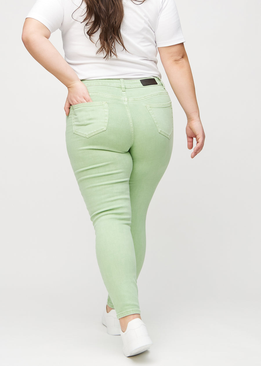 Ljusgröna skinny jeans sedda bakifrån på en plus-size-modell, så att man kan se hela produkten.
