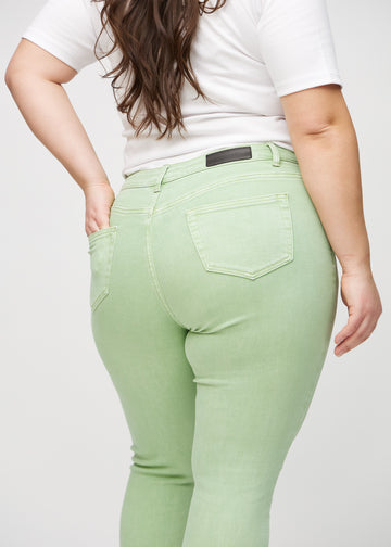 Ljusgröna skinny jeans sedda bakifrån på nära håll på en plus-size-modell för att visa detaljer.