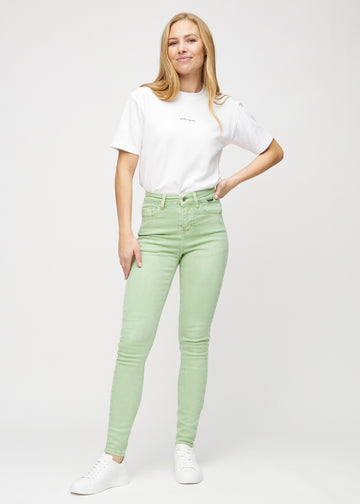 Helbild av modell i ljusgröna skinny jeans.