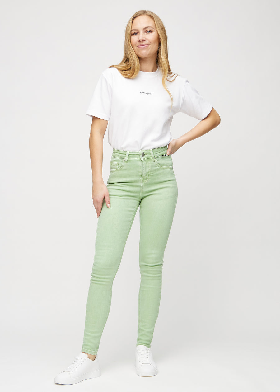Helbild av modell i ljusgröna skinny jeans.