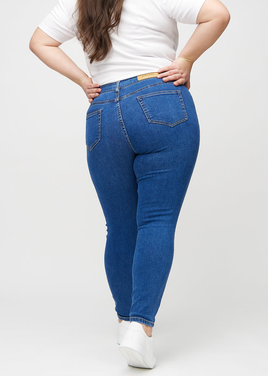 Skinnyjeans för kvinnor i mörkblå, färgen Oceans. Bakifrån på en plus size-modell, så att hela passformen syns.