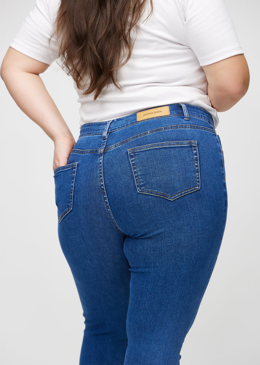 Skinnyjeans för kvinnor i mörkblå, färgen Oceans. Närbild bakifrån på en plus size-modell som visar detaljerna.