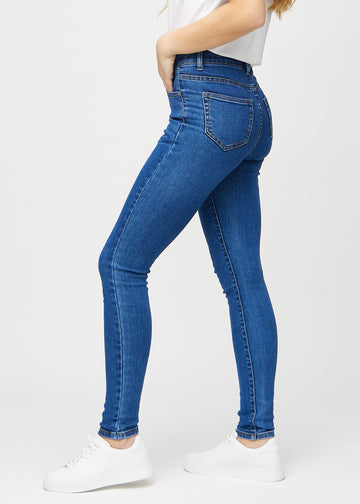 Skinnyjeans för kvinnor i mörkblå, färgen Oceans. Från sidan på en modell.