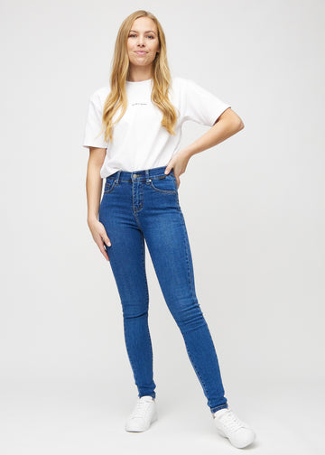 Skinnyjeans för kvinnor i mörkblå, färgen Oceans. Helbild av en modell i jeansen.