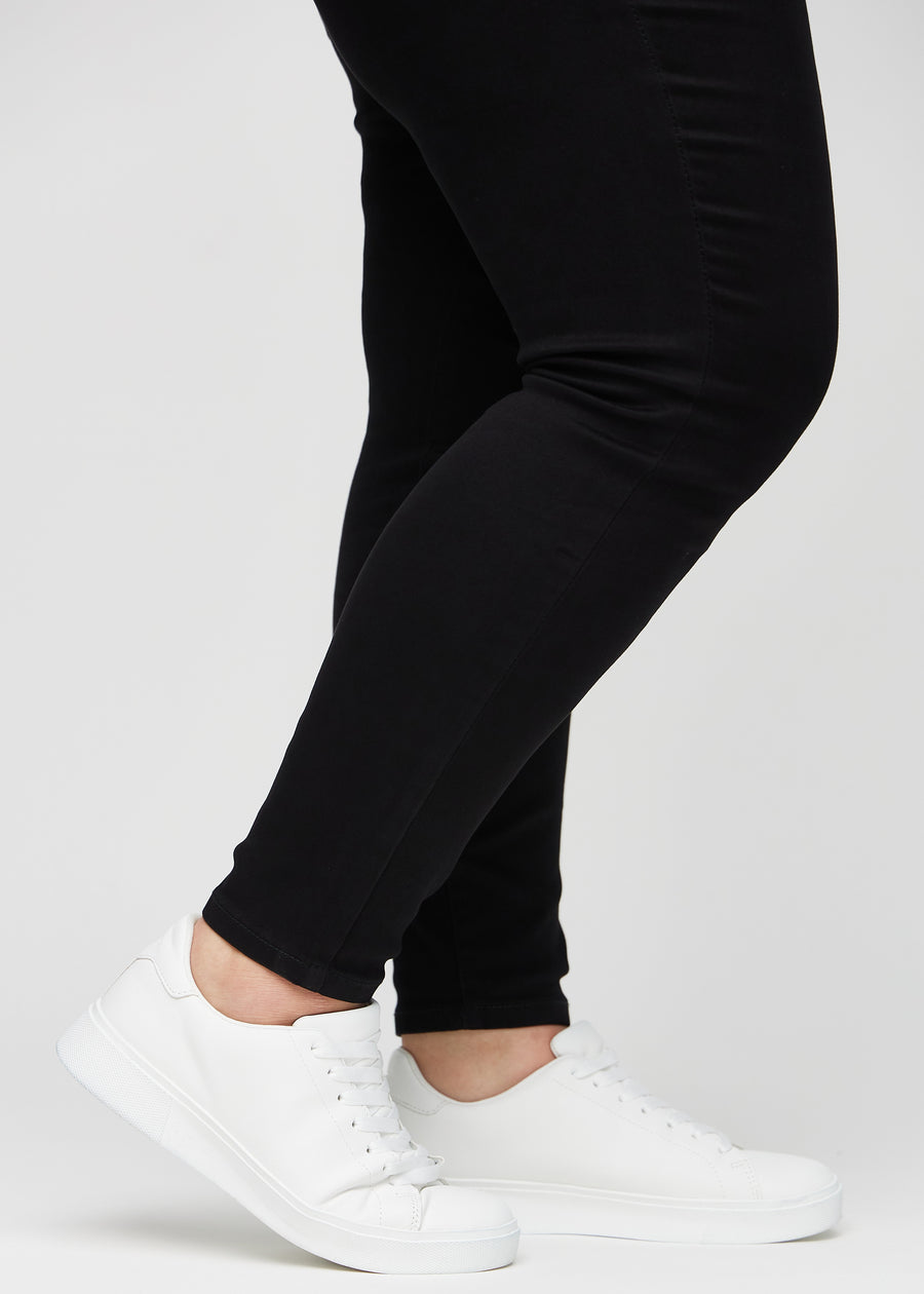 Anklarna på en plus size-modell, så att man kan se hur tajt jeansen sitter i en Skinny passform.