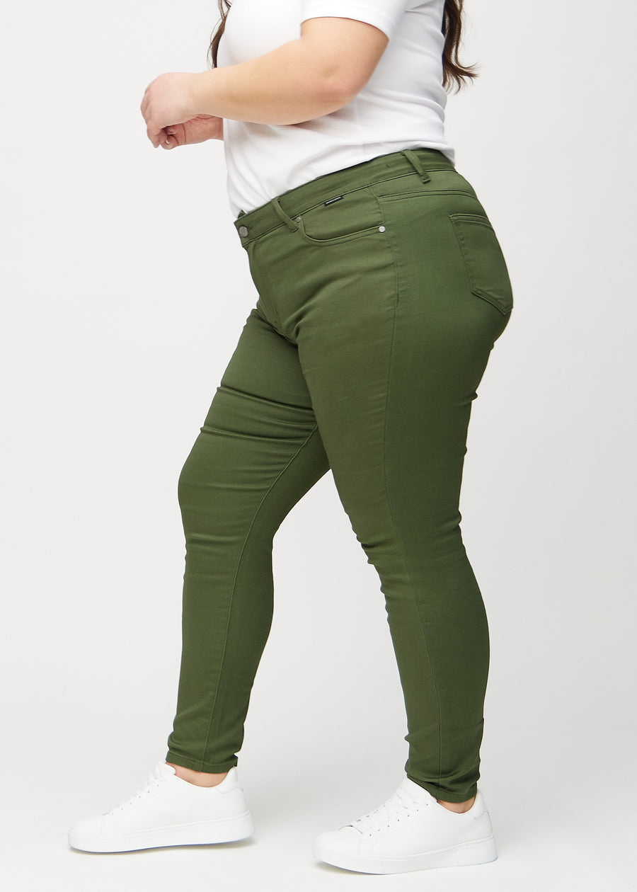 Skinnyjeans för kvinnor i mörkgrön, färgen Renewals. Från sidan på en plus size-modell.