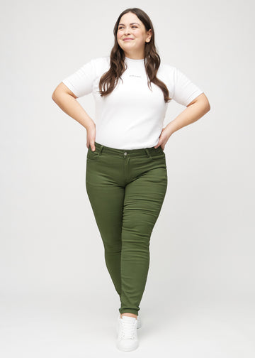 Skinnyjeans för kvinnor i mörkgrön, färgen Renewals. Helbild av en plus size-modell i jeansen.