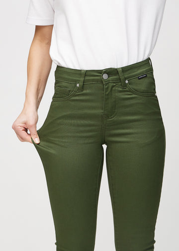 Skinnyjeans för kvinnor i mörkgrön, färgen Renewals. En modell drar i jeanstyget vid låret för att visa stretchen.
