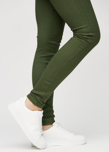 Skinnyjeans för kvinnor i mörkgrön, färgen Renewals. Närbild vid anklarna på en modell som visar de åtsittande bensluten.