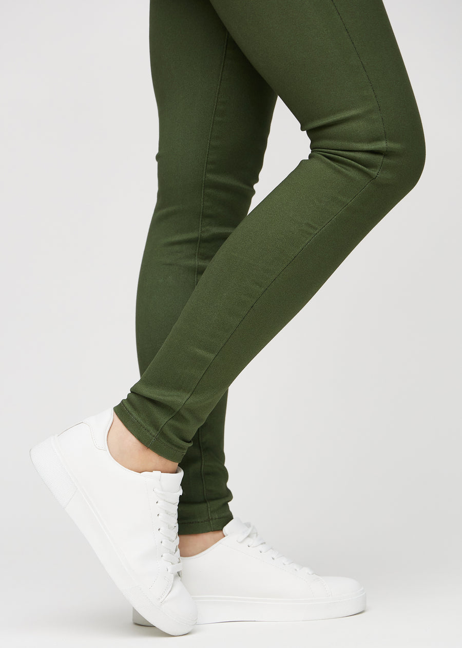 Skinnyjeans för kvinnor i mörkgrön, färgen Renewals. Närbild vid anklarna på en modell som visar de åtsittande bensluten.