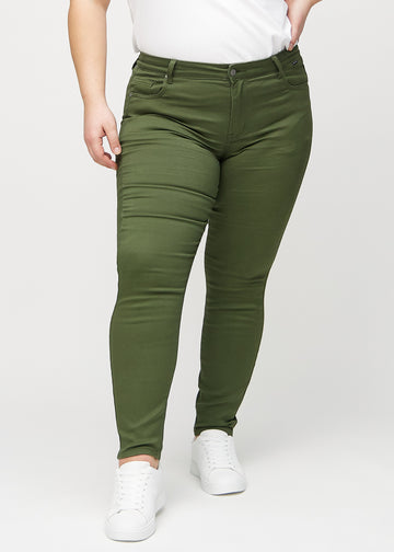 Skinnyjeans för kvinnor i mörkgrön, färgen Renewals. Framifrån på en plus size-modell, med nära passform runt benen.