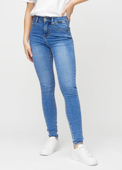 Skinnyjeans för kvinnor i blå, färgen Rivers. Framifrån på en modell, med nära passform runt benen.