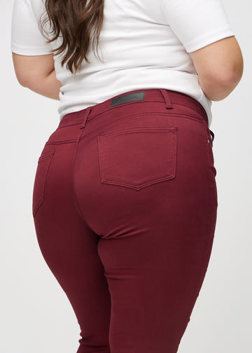 Skinnyjeans för kvinnor i mörkröd, färgen Santas. Närbild bakifrån på en plus size-modell som visar detaljerna.