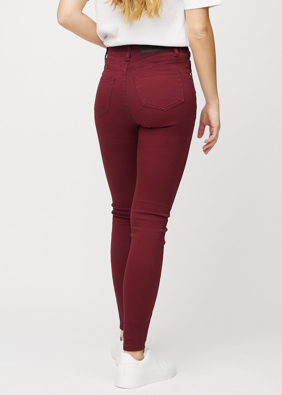 Skinnyjeans för kvinnor i mörkröd, färgen Santas. Bakifrån på en modell, så att hela passformen syns.
