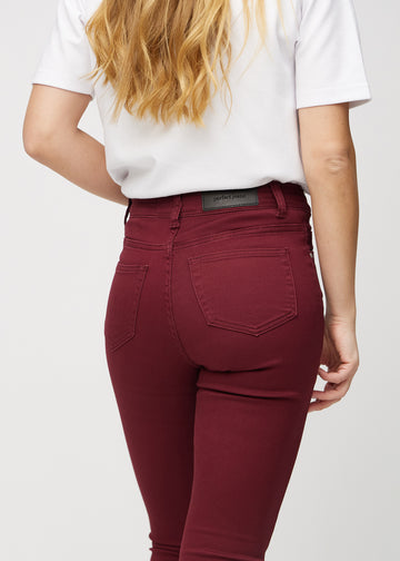 Skinnyjeans för kvinnor i mörkröd, färgen Santas. Närbild bakifrån på en modell som visar detaljerna.