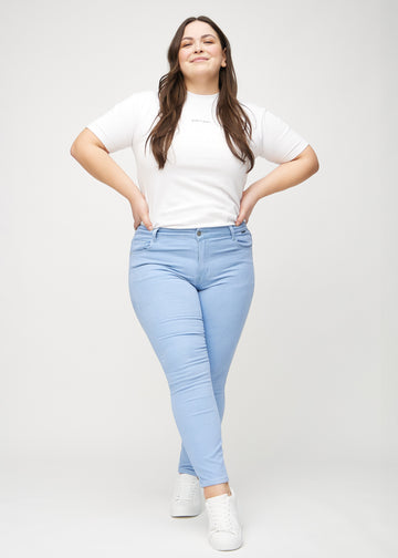 Skinnyjeans för kvinnor i ljusblå, färgen Skies. Helbild av en plus size-modell som bär jeansen.