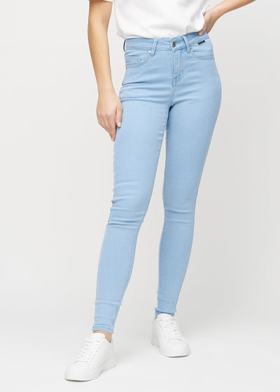 Skinnyjeans för kvinnor i ljusblå, färgen Skies. Framifrån på en modell, med nära passform runt benen.