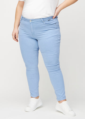 Skinnyjeans för kvinnor i ljusblå, färgen Skies. Framifrån på en plus size-modell, med nära passform runt benen.