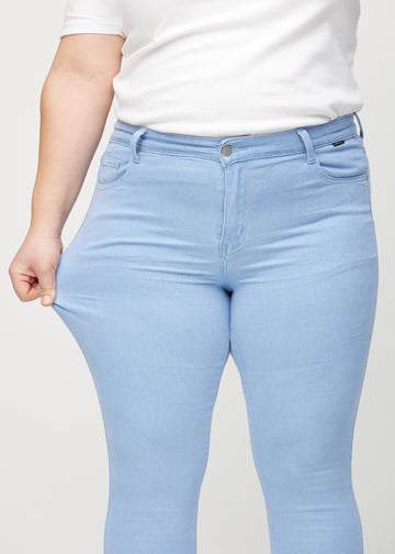 Skinnyjeans för kvinnor i ljusblå, färgen Skies. En plus size-modell drar i jeanstyget vid låret för att visa stretchen.