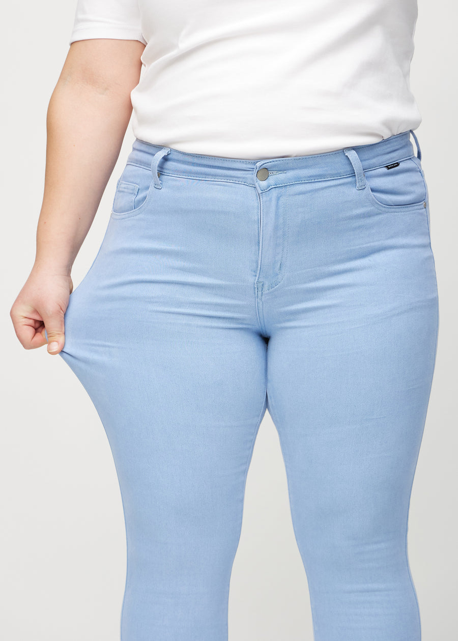 Skinnyjeans för kvinnor i ljusblå, färgen Skies. En plus size-modell drar i jeanstyget vid låret för att visa stretchen.