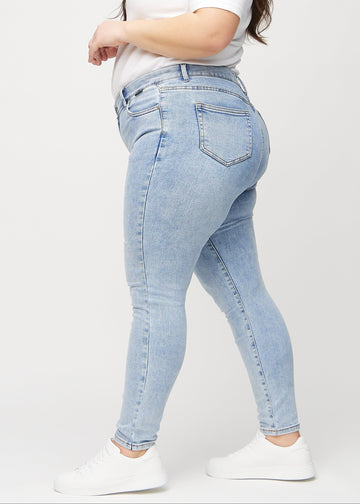 Skinnyjeans för kvinnor i ljusblå, färgen Waves. Från sidan på en plus size-modell.