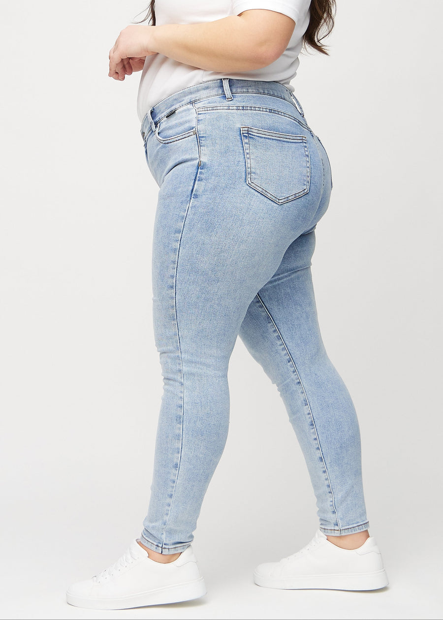 Skinnyjeans för kvinnor i ljusblå, färgen Waves. Från sidan på en plus size-modell.