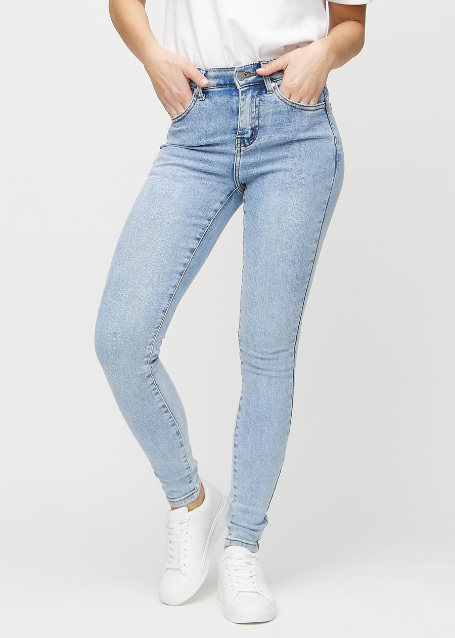 Skinnyjeans för kvinnor i ljusblå, färgen Waves. Framifrån på en modell, med nära passform runt benen.