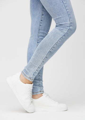 Skinnyjeans för kvinnor i ljusblå, färgen Waves. Närbild vid anklarna på en modell som visar de åtsittande bensluten.