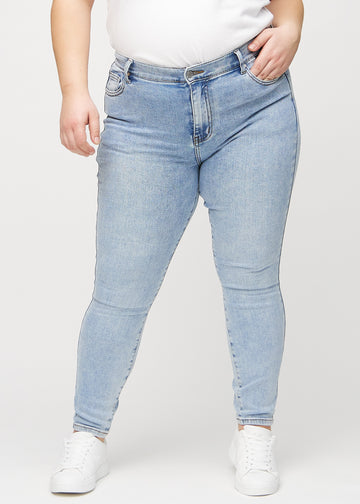 Skinnyjeans för kvinnor i ljusblå, färgen Waves. Framifrån på en plus size-modell, med nära passform runt benen.