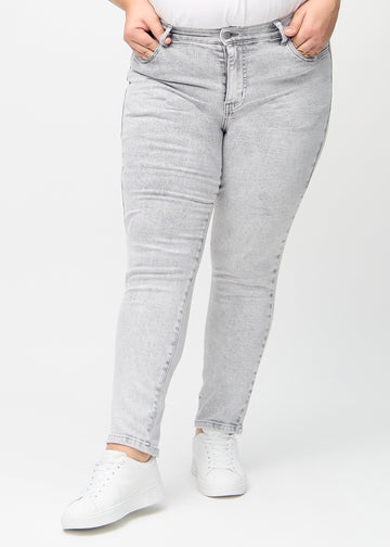 Slimjeans för kvinnor i ljusgrå, färgen Ashes. Framifrån på en plus size-modell, med kroppsnära ben och lite mer utrymme vid anklarna.