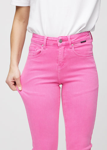 Slimjeans för kvinnor i ljusrosa, färgen Flamingos. En modell drar i jeanstyget vid låret för att visa stretchen.