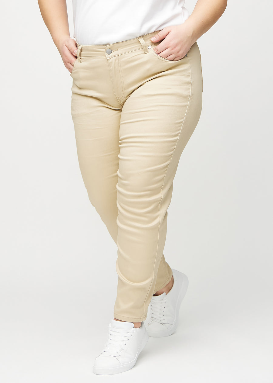Slimjeans för kvinnor i beige, färgen Gazelles. Framifrån på en plus size-modell, med kroppsnära ben och lite mer utrymme vid anklarna.