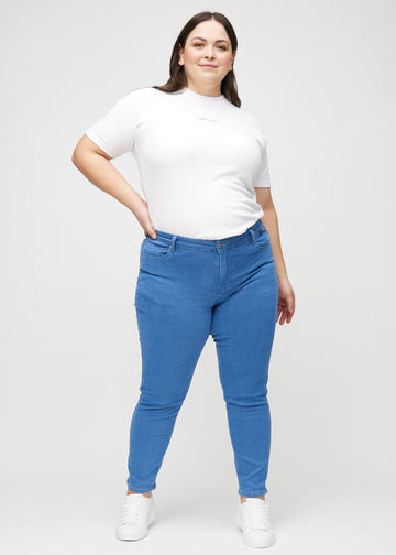 Slimjeans för kvinnor i blå, färgen Geraniums. Helbild av en plus size-modell som bär jeansen.