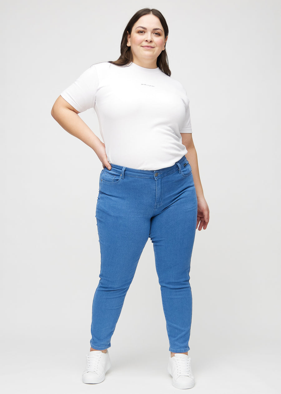 Slimjeans för kvinnor i blå, färgen Geraniums. Helbild av en plus size-modell som bär jeansen.