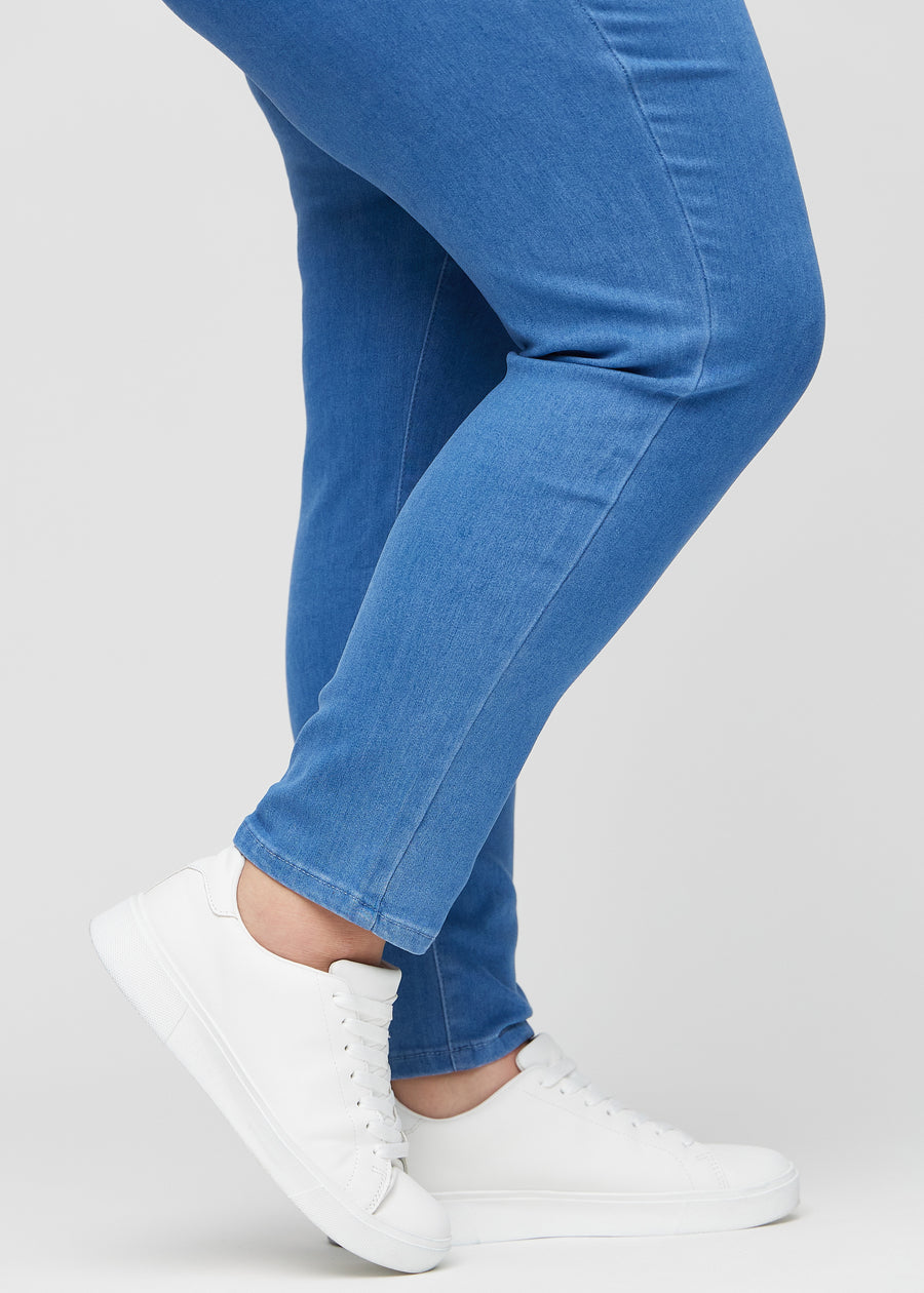 Slimjeans för kvinnor i blå, färgen Geraniums. Närbild vid anklarna på en plus size-modell som visar passformen vid bensluten.