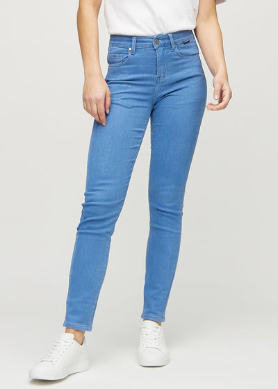 Slimjeans för kvinnor i blå, färgen Geraniums. Framifrån på en modell, med kroppsnära ben och lite mer utrymme vid anklarna.