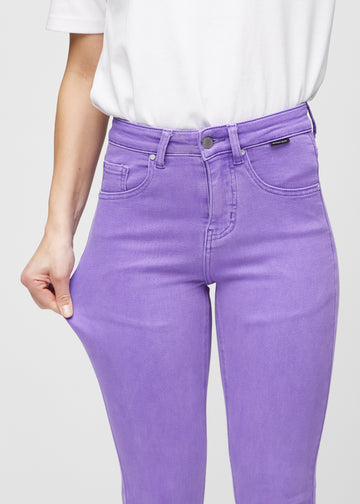 Slimjeans för kvinnor i lila, färgen Lavenders. En modell drar i jeanstyget vid låret för att visa stretchen.