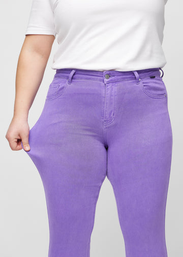 Slimjeans för kvinnor i lila, färgen Lavenders. En plus size-modell drar i jeanstyget vid låret för att visa stretchen.