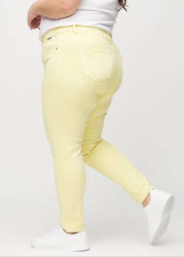 Slimjeans för kvinnor i ljusgul, färgen Lemonades. Från sidan på en plus size-modell.