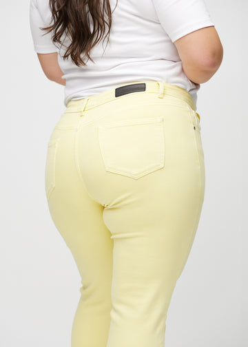 Slimjeans för kvinnor i ljusgul, färgen Lemonades. Närbild bakifrån på en plus size-modell som visar detaljerna.